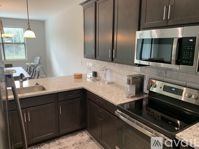 A kitchen with a stove, sink, and microwave.
