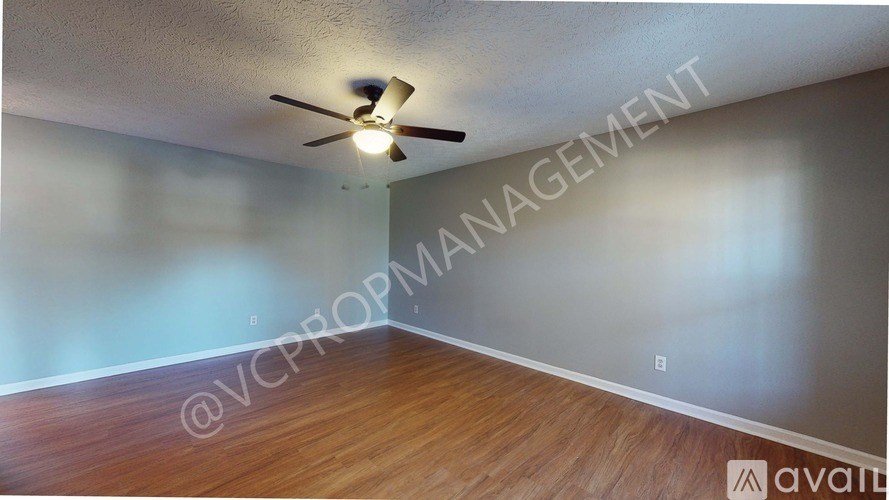 A room with a ceiling fan and wooden flooring.