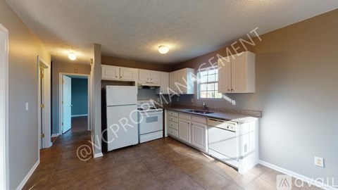 A kitchen with white cabinets and appliances in a house.