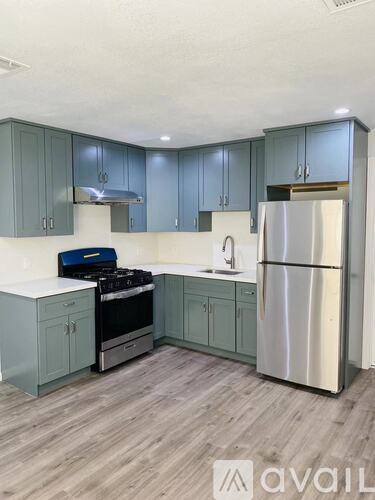 A kitchen with a stove, sink, and refrigerator.