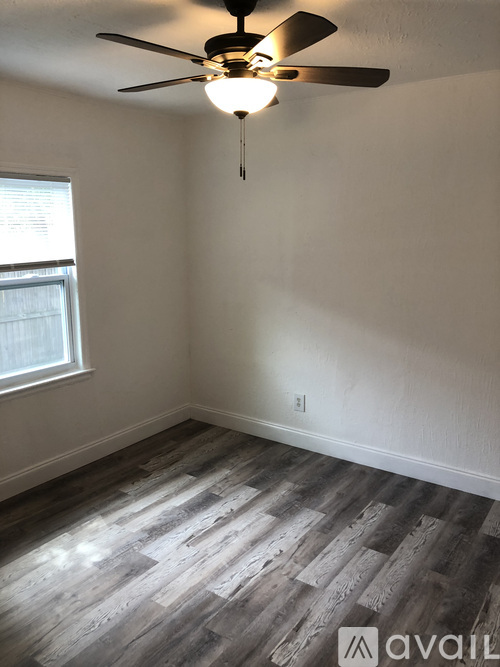 A room with a ceiling fan and wooden flooring.
