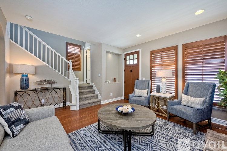 A living room with a staircase and a dining table.