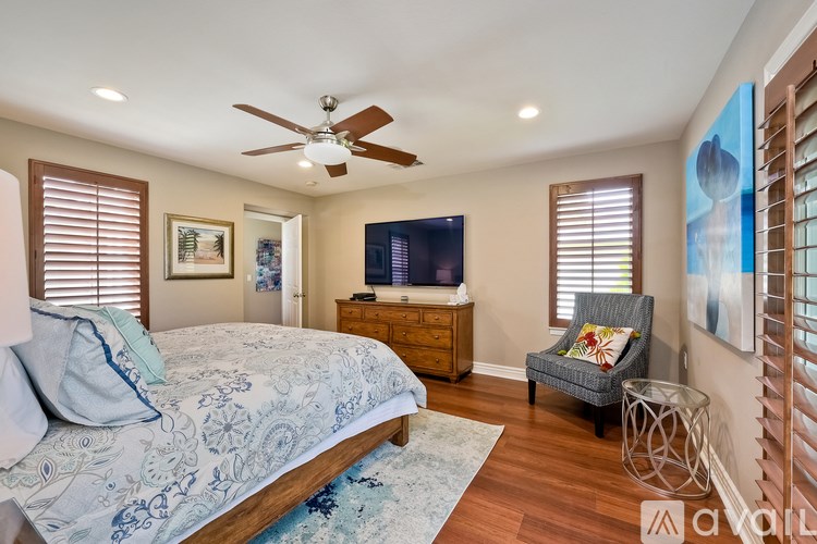 A bedroom with a bed, chair, and ceiling fan.