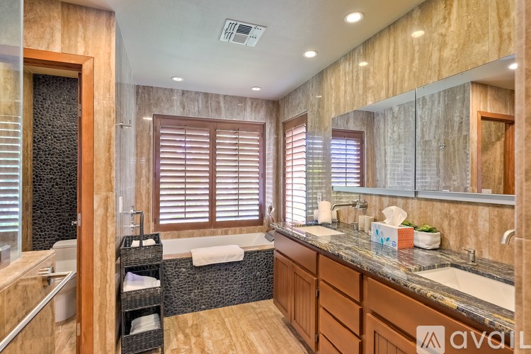 A bathroom with a tub, sink, and wooden cabinets.