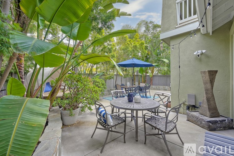 A patio with a table and chairs surrounded by green plants.