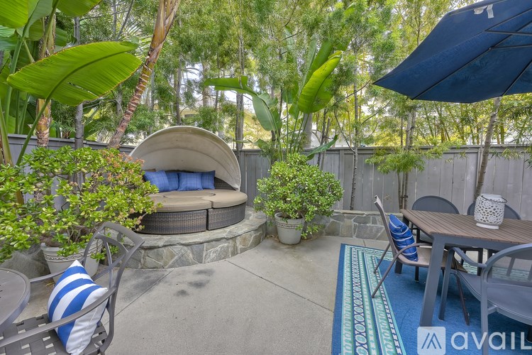 A patio with a round stone structure and a table with chairs.