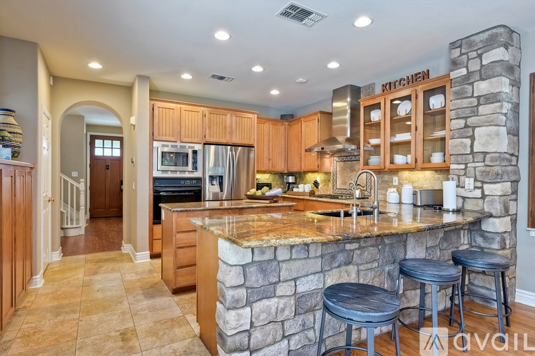 A kitchen with a stone counter and wooden cabinets.