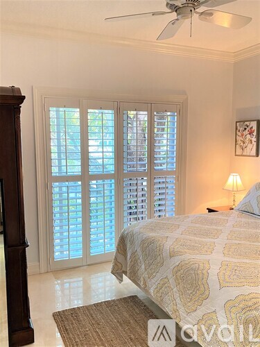 A bedroom with a bed, a ceiling fan, and a window with blinds.
