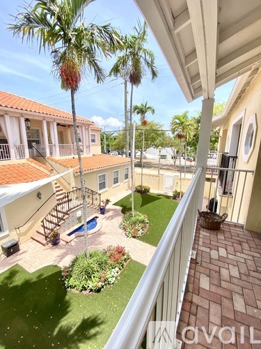 A balcony overlooks a small pool and a landscaped yard.