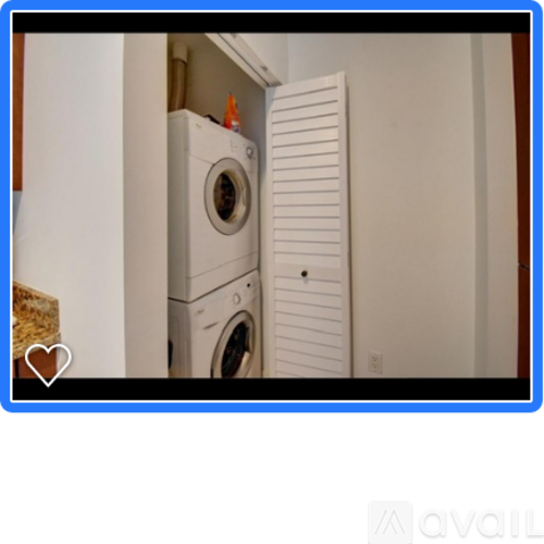 A white washing machine is stacked on top of another in a small space.