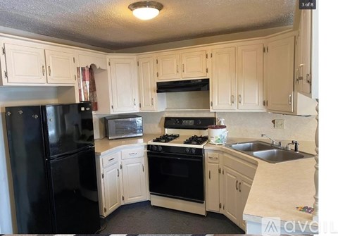 A kitchen with white cabinets and black appliances.