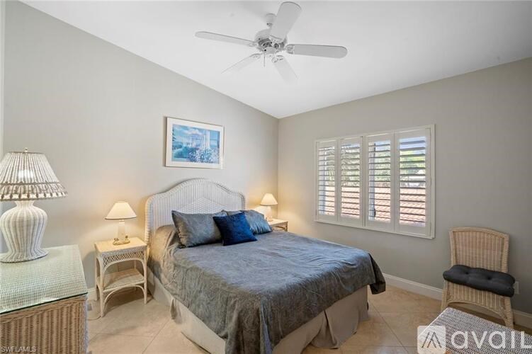 A bedroom with a bed, a chair, and a ceiling fan.