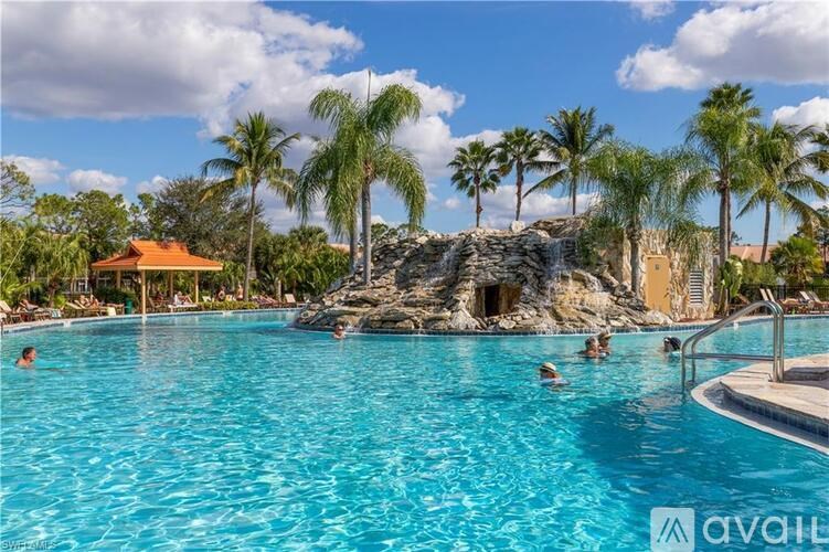 A pool with people swimming and a rock formation in the background.