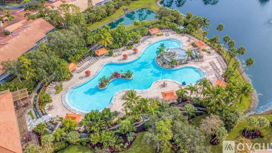 A large swimming pool surrounded by palm trees and a resort.