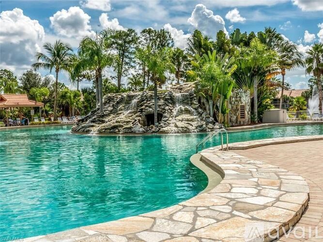 A pool with a waterfall surrounded by palm trees.