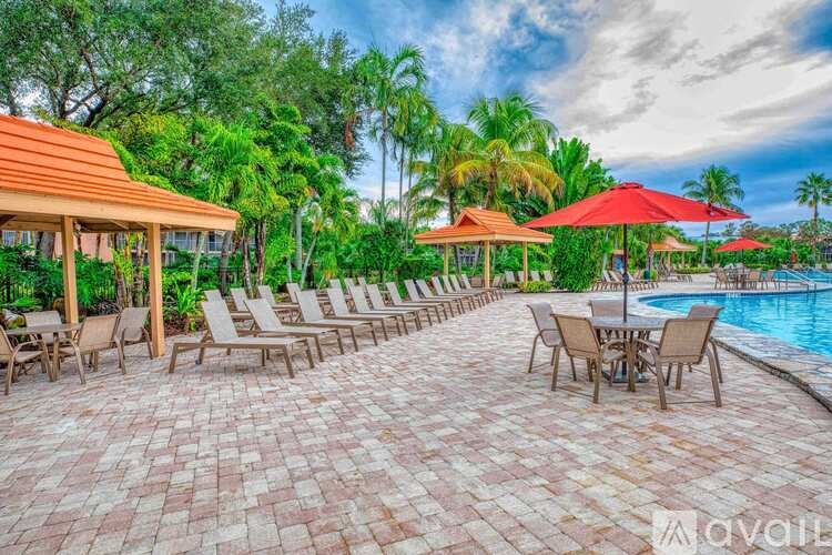 A poolside area with red umbrellas and a table set for dining.