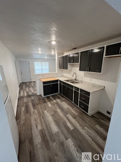 A kitchen with black cabinets and a wooden floor.