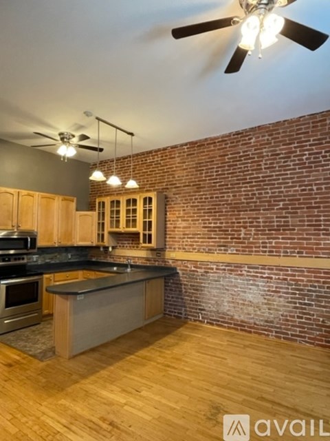 A kitchen with wooden cabinets and a brick wall.