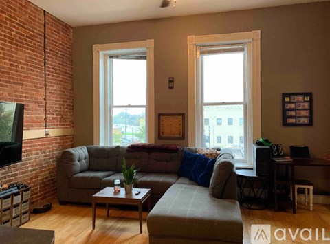 A living room with a grey couch and a coffee table in front of a brick wall.