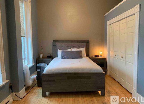 A bedroom with a bed, nightstand, and a window with blinds.