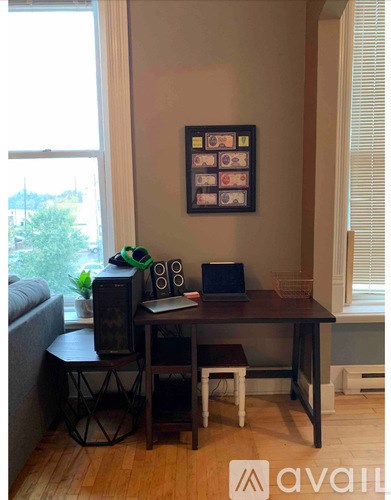 A room with a table, a laptop, and a television.