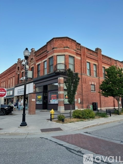 A street view of a red brick building with a black car parked in front.