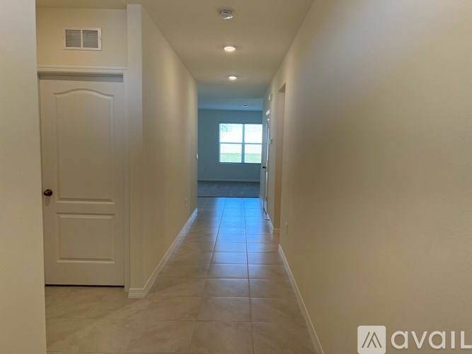 A long hallway with a white door on the left and a window on the right.
