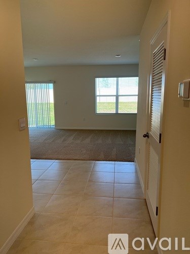 A hallway with tiled flooring and a window with blinds.