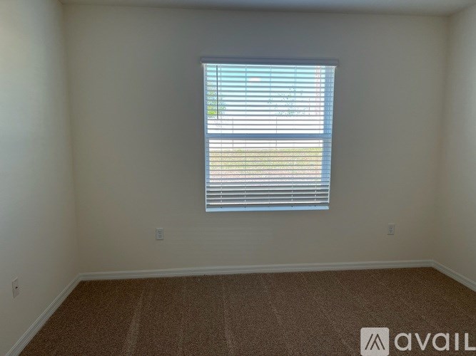 A room with a carpeted floor and a window with blinds.