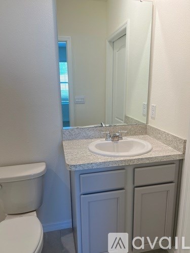 A bathroom with a toilet, sink, and mirror.