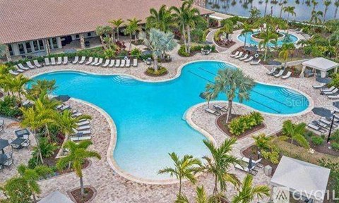 A large swimming pool surrounded by palm trees and lounge chairs.