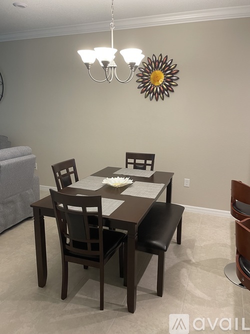 A dining room with a table set for two and a chandelier hanging from the ceiling.