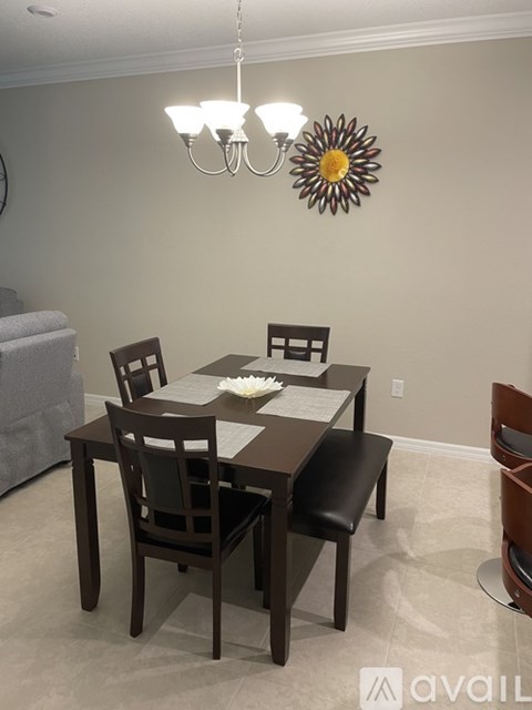 A dining room with a table set for two and a chandelier hanging from the ceiling.