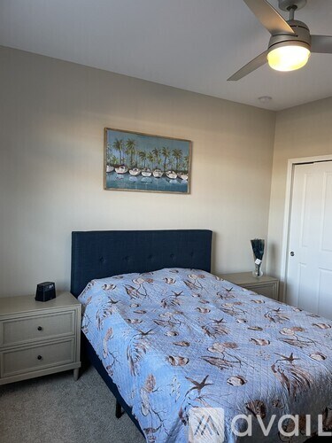 A bedroom with a bed, nightstand, and a painting on the wall.