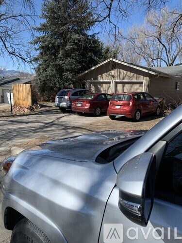 A silver car is parked in front of a house with a sign that reads "avail".