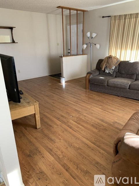 A living room with a grey couch and wooden floors.