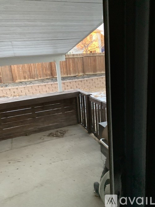 A patio with a white roof and a wooden fence.