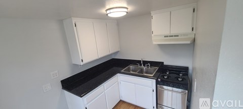 A kitchen with white cabinets and black countertops.
