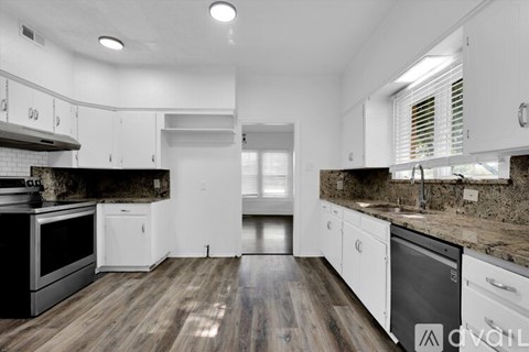 A modern kitchen with white cabinets and a wooden floor.