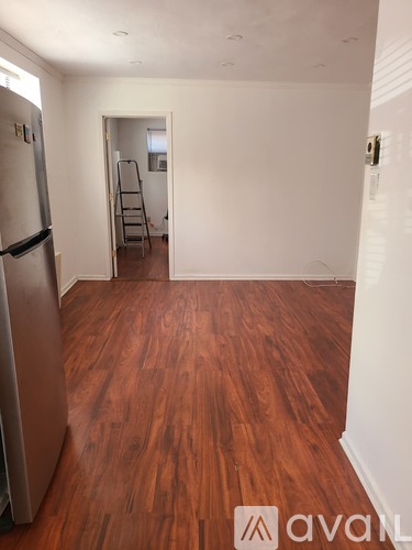 A room with a tan floor and a black table with four chairs.