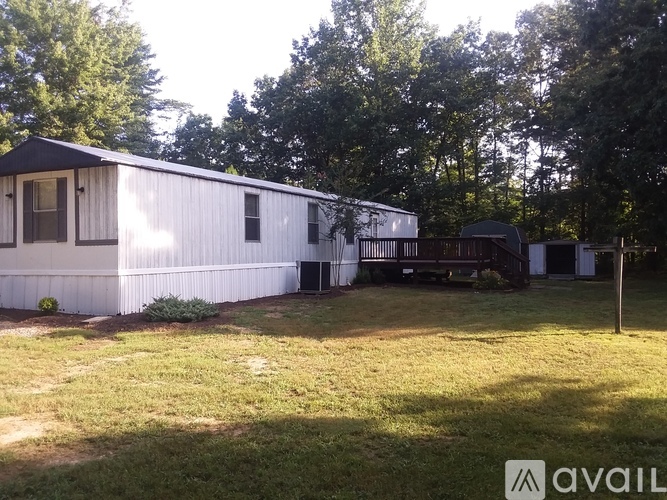 A white mobile home sits in a grassy backyard.