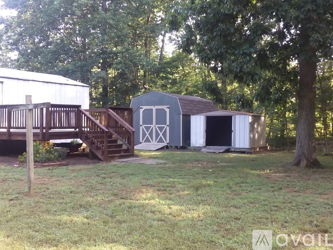A backyard with a deck, a shed, and a tree.