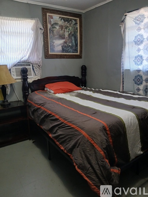 A bed with a striped comforter and a picture on the wall.