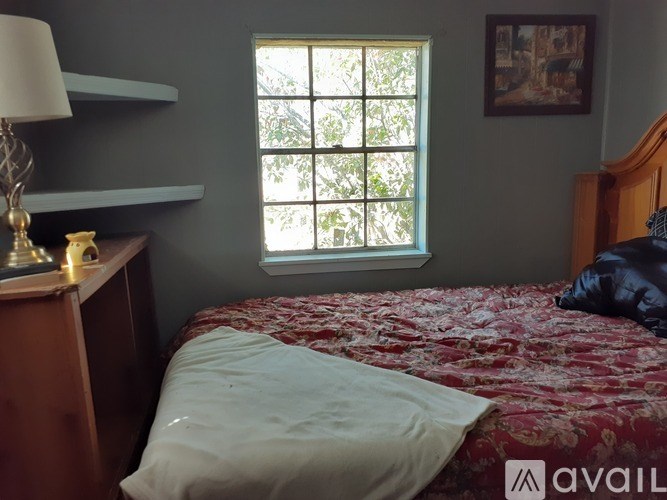 A bedroom with a bed, a lamp, and a window.