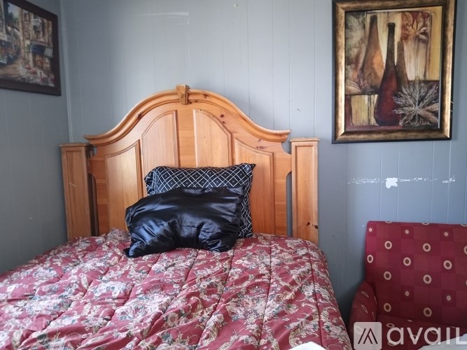 A bed with a wooden headboard and a red and white patterned pillow.