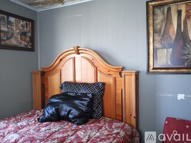 A bed with a wooden headboard and a red and white patterned comforter with a black pillow on it.