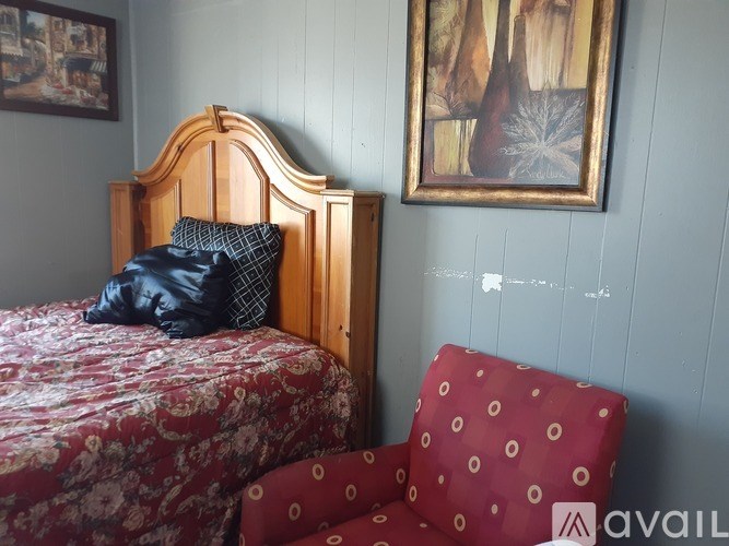 A bed with a red patterned bedspread and a red chair with white circles on it.