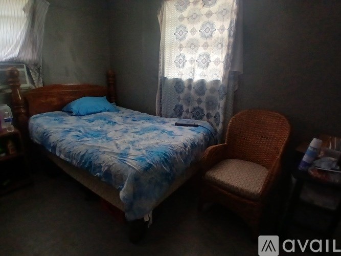 A bedroom with a bed, a chair, and a window with curtains.