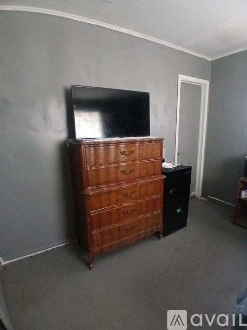 A wooden chest of drawers with a flat screen TV on top.