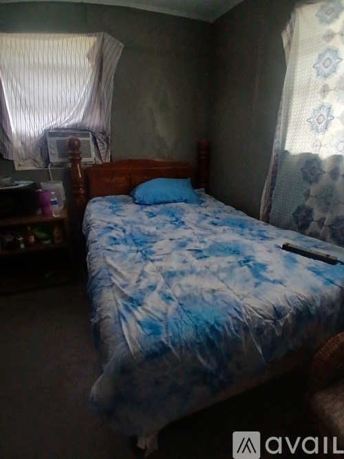 A bed with a blue and white comforter is in the image.